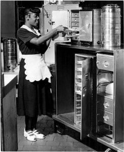 A Barnes Hospital pantry maid with one of the specially designed carts used in the airline model of food service, c. 1950s.