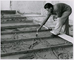 Nivola sculpting the sand in the forms, circa 1960