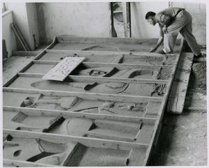 Nivola sculpting the sand in the forms referencing a small model, circa 1960