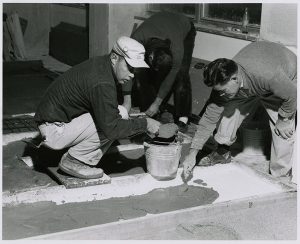 Nivola and assistant pouring concrete into the finished forms, circa 1960