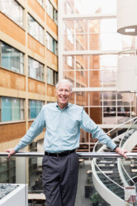 Paul Schoening, Director of Becker Library, standing in front of glass barrier overlooking the atrium of the library.
