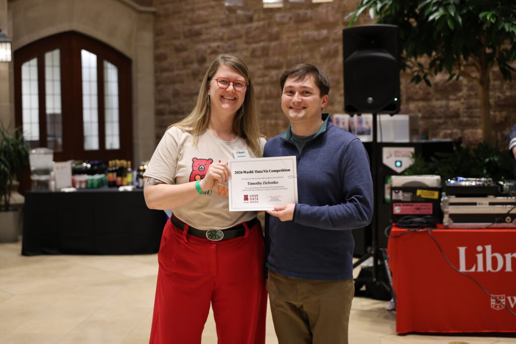 A woman and a man standing side-by-side, holding a certificate for the 2026 WashU Data Viz Competition awarded to Timothy Zielonko.